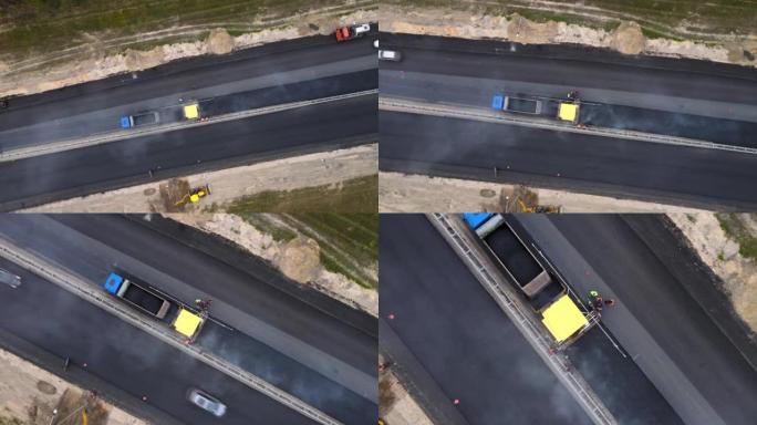 无人机向下移动到黄色道路摊铺机和工人。高速公路上的道路工程