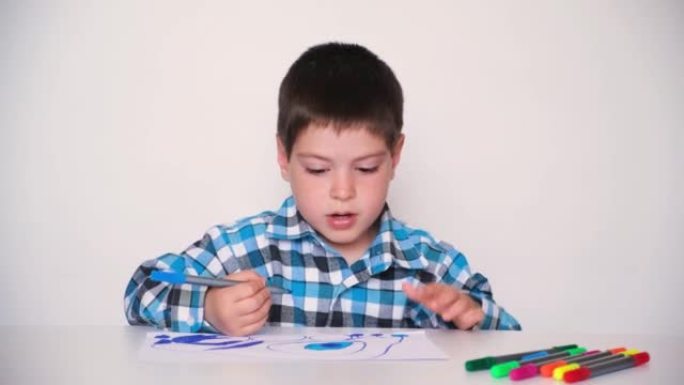 一个4岁的男孩给一幅画上色，然后在白色背景上看着相机说话。