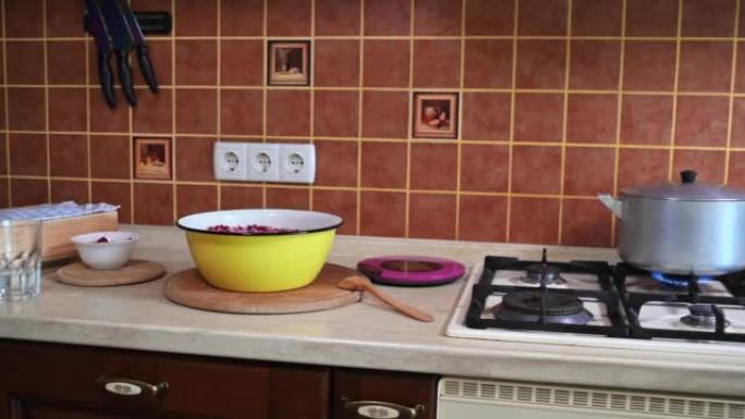 家用木制乡村厨房的炉灶上有带红醋栗的碗、食物秤和开水锅的工作台