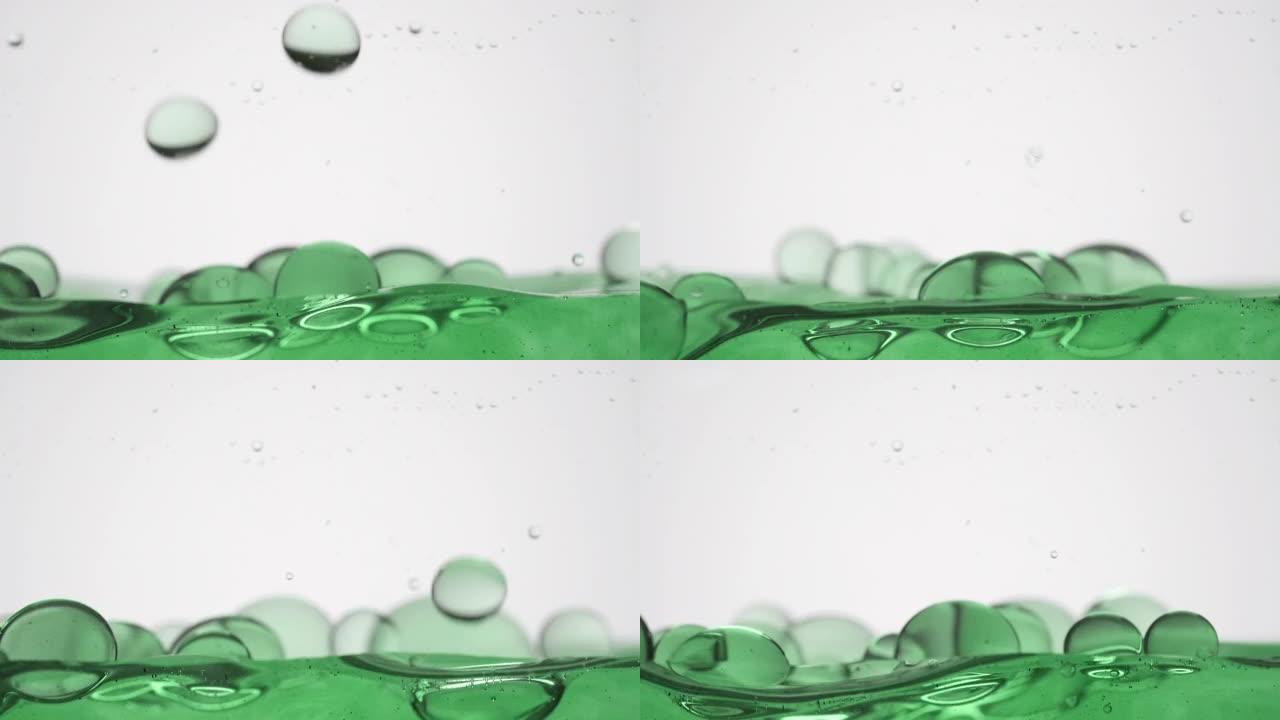 绿色气泡掉落到绿色表面在灰色背景上弹跳