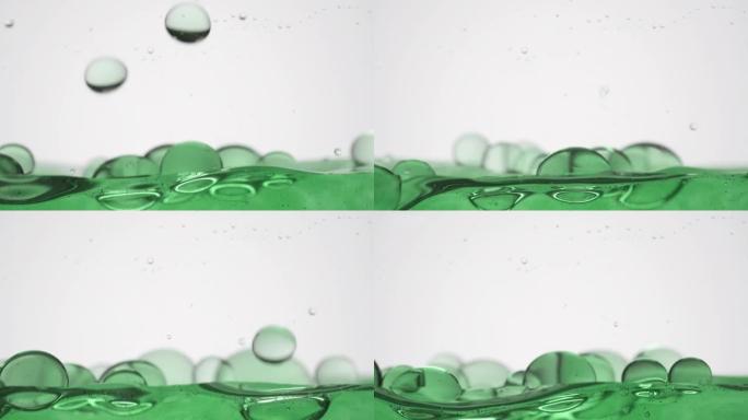 绿色气泡掉落到绿色表面在灰色背景上弹跳