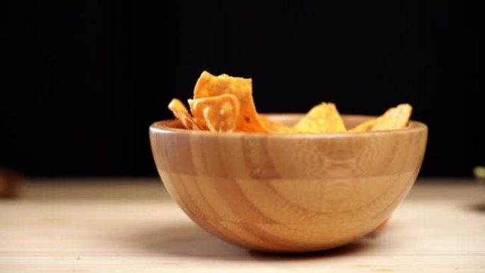 玉米饼碎片落在盘子里的慢动作镜头。落在木碗里的玉米片。传统墨西哥食物。鳄梨调味酱玉米片是鳄梨，番茄和