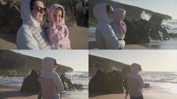 春天妈妈手捧孩子站在海边，穿着暖和的衣服手持视频效果