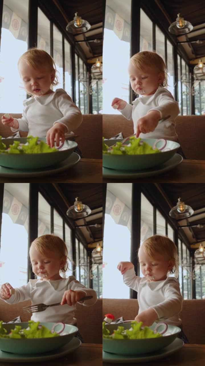 一个蓝眼睛的小女孩正在吃东西-她用手从盘子里取食物，然后涂在脸上。