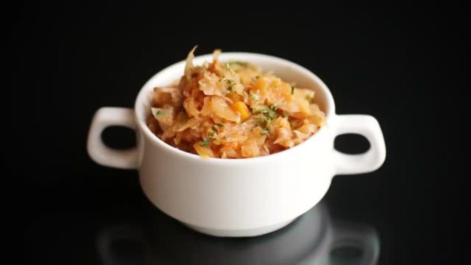 在黑色背景的碗里炖胡萝卜和香料的卷心菜。