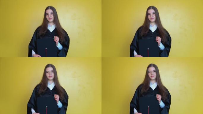 一名大学毕业生拿着一顶红色流苏的硕士帽子站在镜头前。一名年轻女子在黄色背景上长直发的正面照片