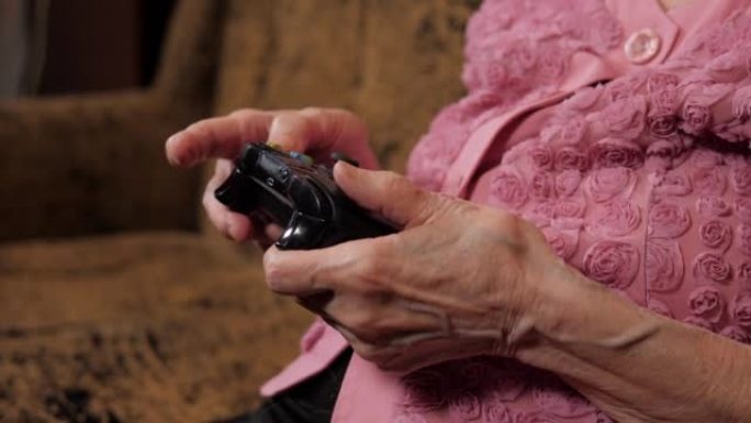 一个祖母在家玩电子游戏的特写镜头，她拿着操纵杆。