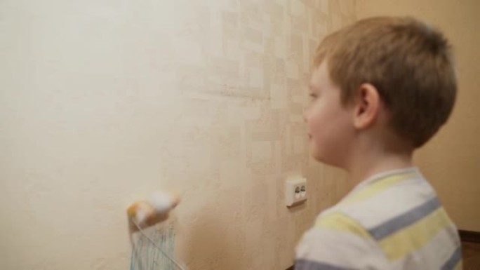 高加索儿童，男孩在墙上滚动油漆滚筒，玩耍