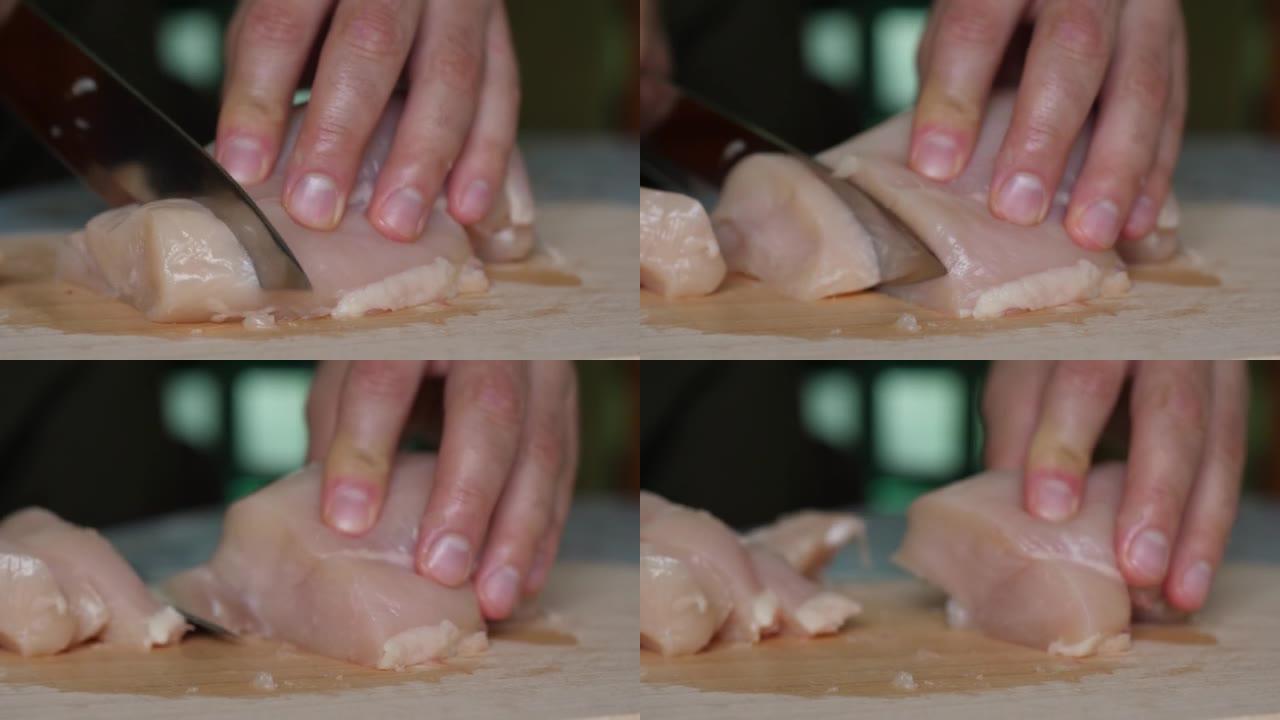 在切好的木板上关闭鸡柳。男人的手刀切片精致的火鸡鱼片在木制切板上。厨师切鸡胸肉，生白肉，厨师煮鸡胸肉