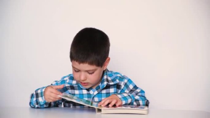 一个学龄前男孩读一本书，合上书，然后将其推开。