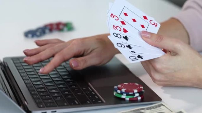 人与笔记本电脑扑克牌的赌场筹码堆一起工作