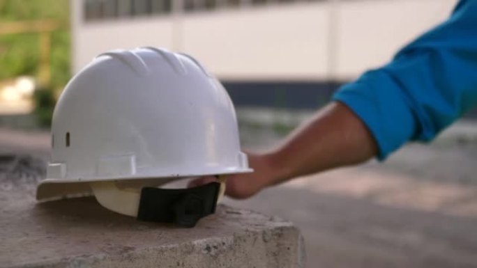 一名建筑工人的特写镜头，在一座在建桥梁的钢筋混凝土桥墩上留下了一顶保护性的白色安全帽。建筑工人在建筑