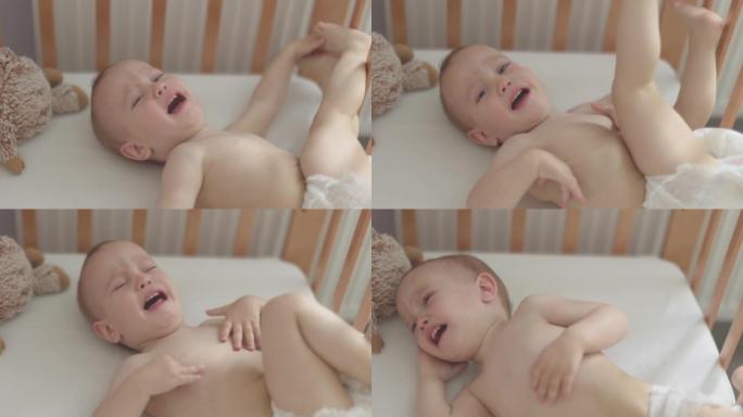 画像中哭着尖叫的裸婴婴儿，躺在婴儿床的摇篮里