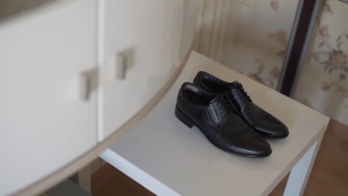 干净的新黑色商务鞋在房间餐具柜附近的桌子上。