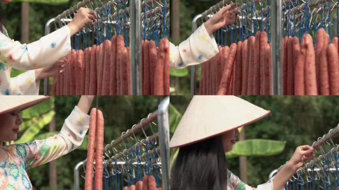 穿着传统服装的越南美女生产中国香肠。中国香肠是春节期间受欢迎的食物之一。