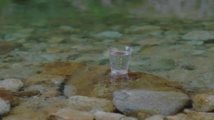在美丽的河流中放有水的玻璃