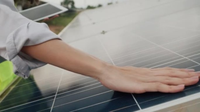 一位年轻女性工程师的特写镜头正在检查光伏太阳能电池板的清洁度执行常规动作，动手太阳能电池板产生能量，