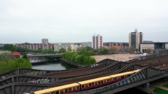 飞越城市河上的钢桥。在多轨铁路上运行的郊区火车。背景中的居民区。德国柏林