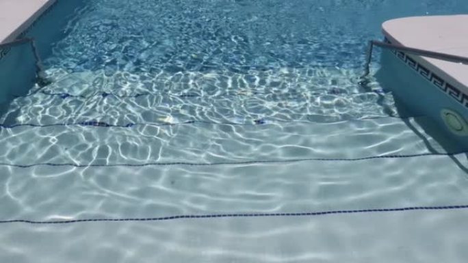 走到阳光普照的游泳池的绿松石表面。抽象反射和折射光