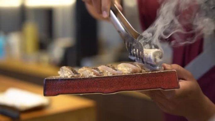 厨师的手在日本餐厅燃烧寿司卷