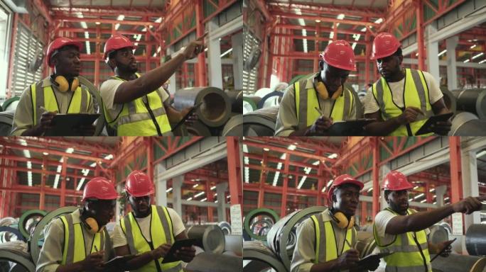 两名身穿制服的非洲男子工人戴着安全帽，拿着平板电脑和剪贴板检查工厂库存。