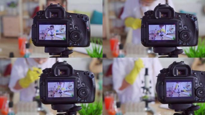 一个十几岁的女孩的肖像视频博客作者在实验室里穿着白大褂和护目镜，看着相机微笑着慢动作