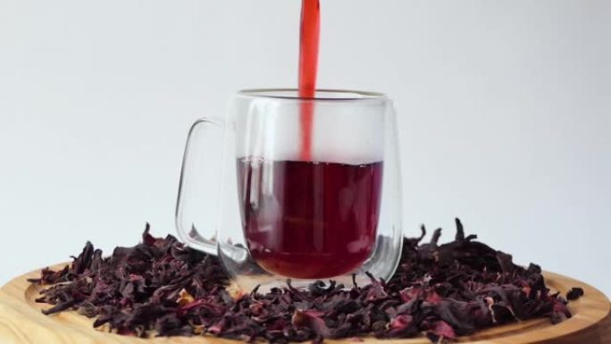 白底玻璃杯中的红茶。将红芙蓉茶倒入带有双壁的透明玻璃中。一杯在木板上旋转的茶。