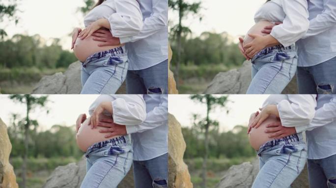 Beautiful pregnant woman and her husband hugging h