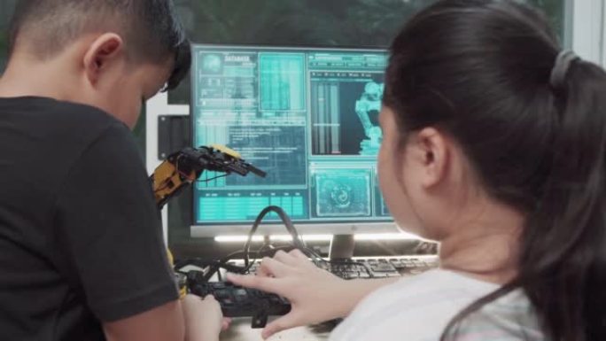 教育主题: 男孩和女孩学习如何在数字平板电脑上控制玩具机器人手臂，科学工程，教育，技术