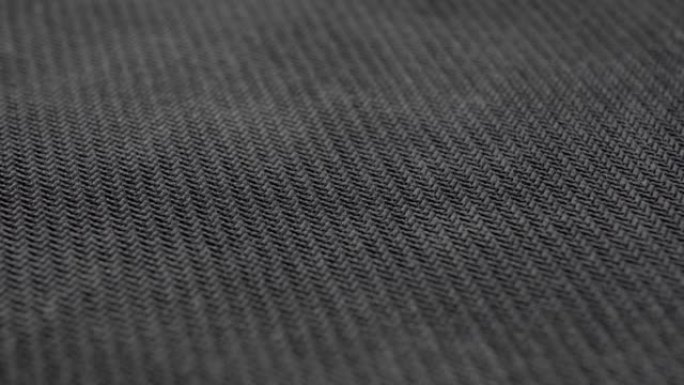 黑色纺织垃圾编织材料。深色尘土纹理织物特写。机织结构。宏