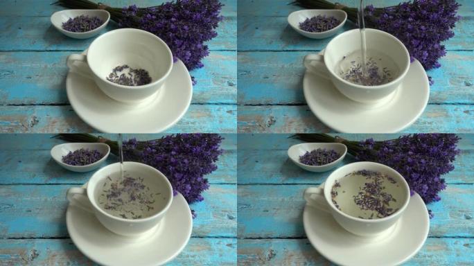 复古木制背景上的淡紫色鲜花茶。茶是在杯子里用热水冲泡的。一股沸水倒入一杯茶中。慢动作。