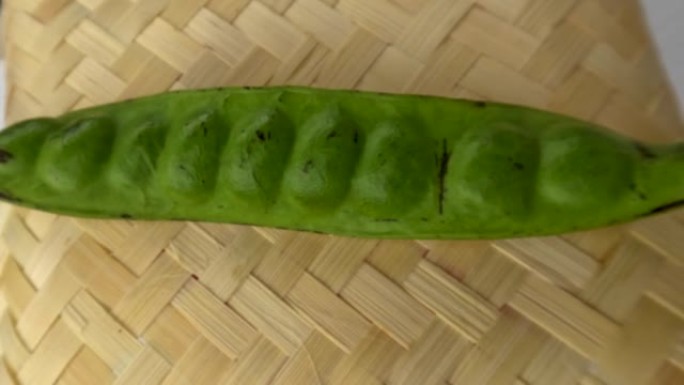 一根绿色的苦豆棒，放在编织的竹基上