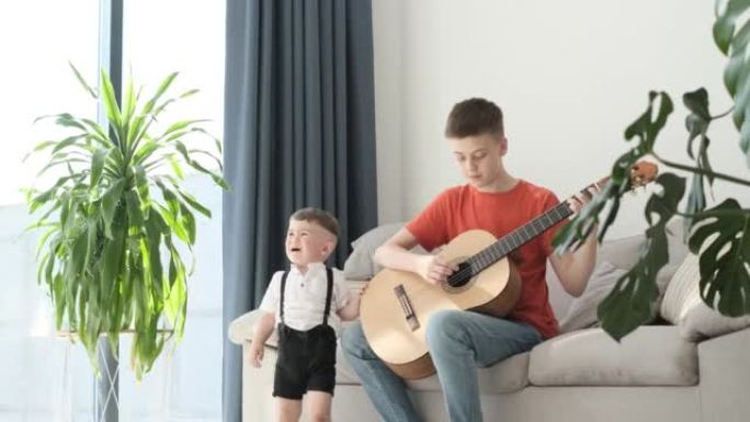 一个小男孩在哭，他的兄弟坐在沙发上弹吉他。
