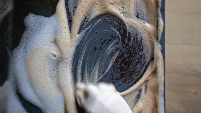 高加索妇女清洁厨房烤箱滴注使用除油剂泡沫和海绵