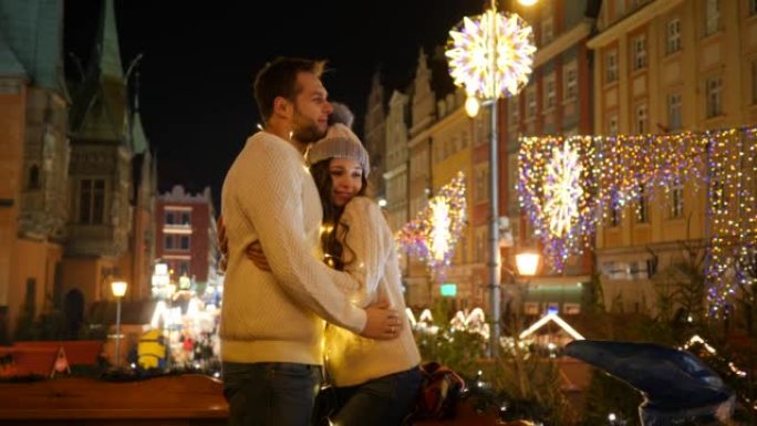年轻可爱的夫妇在市中心的圣诞集市明亮的集市广场上跳舞很开心