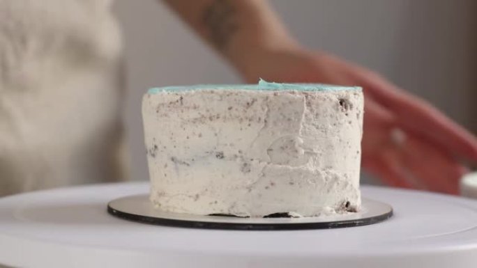 糖果店在圆形蛋糕顶部撒上蓝色奶油，用烹饪刮刀特写