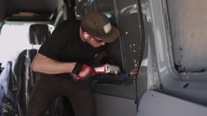 在货车上安装窗户时使用研磨机电动工具的人