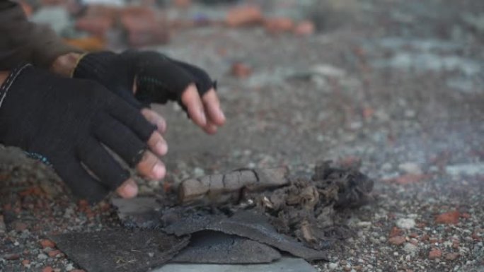 一个无家可归的人冷得发抖，在炉火旁温暖着他的手。