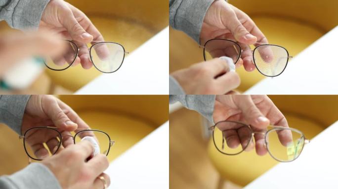 一个男人的手用清洁液喷涂眼镜并用布擦拭的特写镜头
