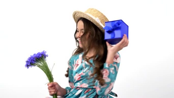 快乐的孩子在夏季草帽转动野花花束矢车菊和礼品盒，春假。
