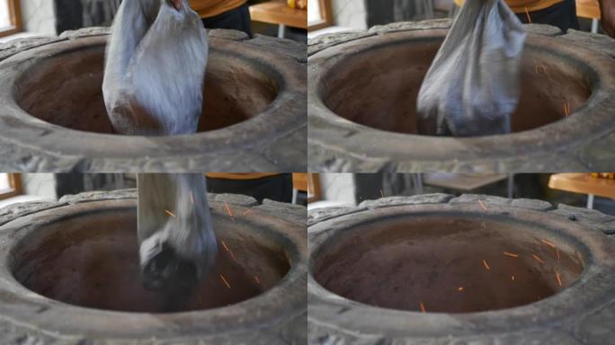 一位亚美尼亚面包师将煤从一个袋子倒入一个里面有火的石头tonir中。将木炭倒入烤面包和埃里温·霍罗瓦
