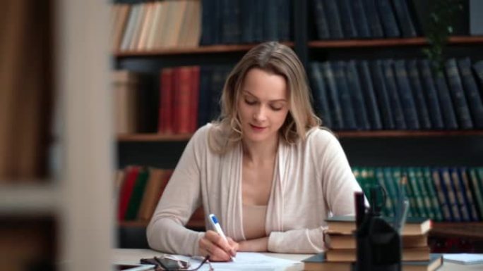 微笑的商务老师科学学术教授年轻女子在图书馆写纸质信笺