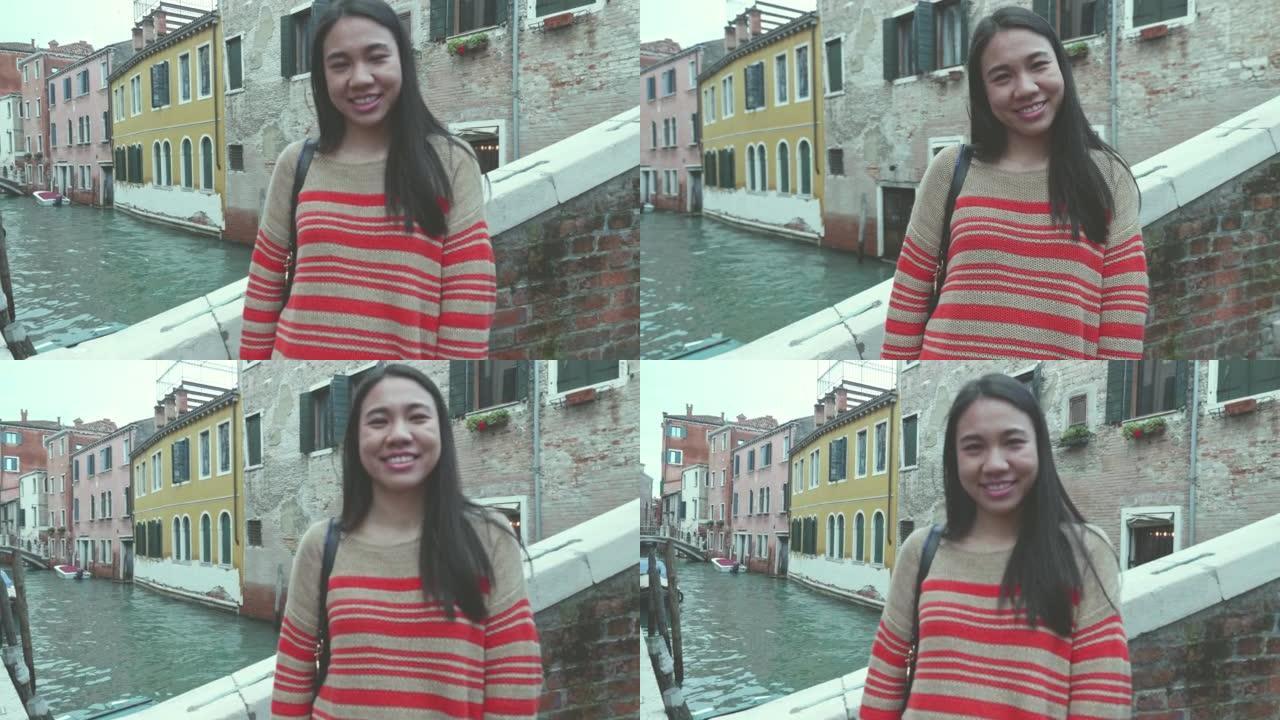 年轻女子独自在威尼斯旅行，在运河和老房子前自拍