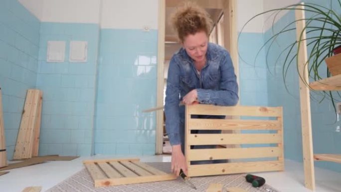 女人用电动螺丝刀在厨房里组装木架子