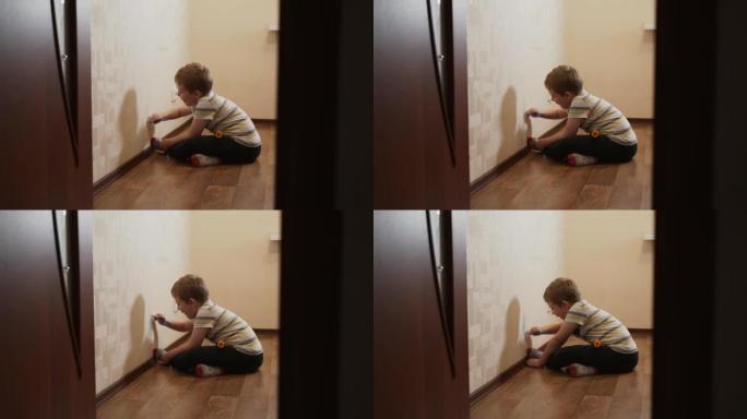 高加索孩子，男孩坐在墙附近，用毡尖笔在墙纸上画画