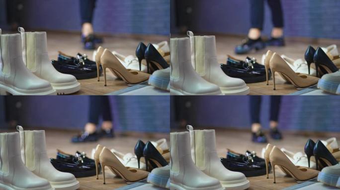 前景不同类型的鞋类。模型在模糊的背景下展示黑色闪亮的鞋子。
