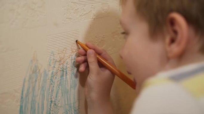 高加索孩子，男孩坐在墙附近，用毡尖笔在墙纸上画画