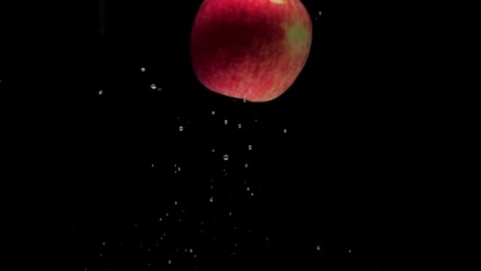 慢动作一个红苹果落入黑色背景的透明水中