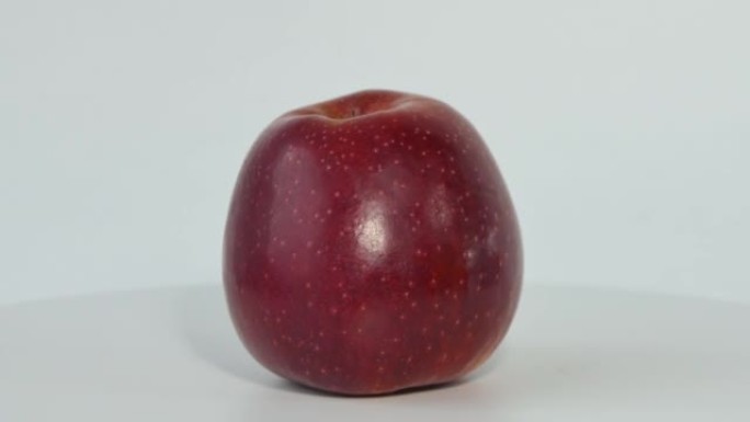 一个完整的红苹果旋转。红苹果的宏观照片。苹果在白色背景上绕其轴旋转。