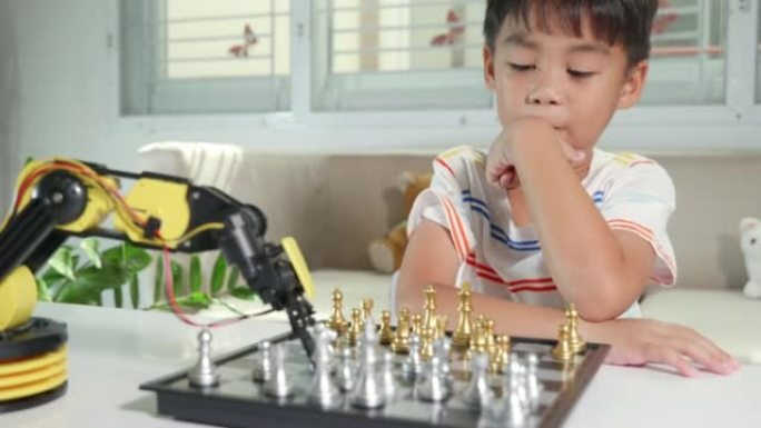 亚洲小男孩正在用机器人机器手臂下棋